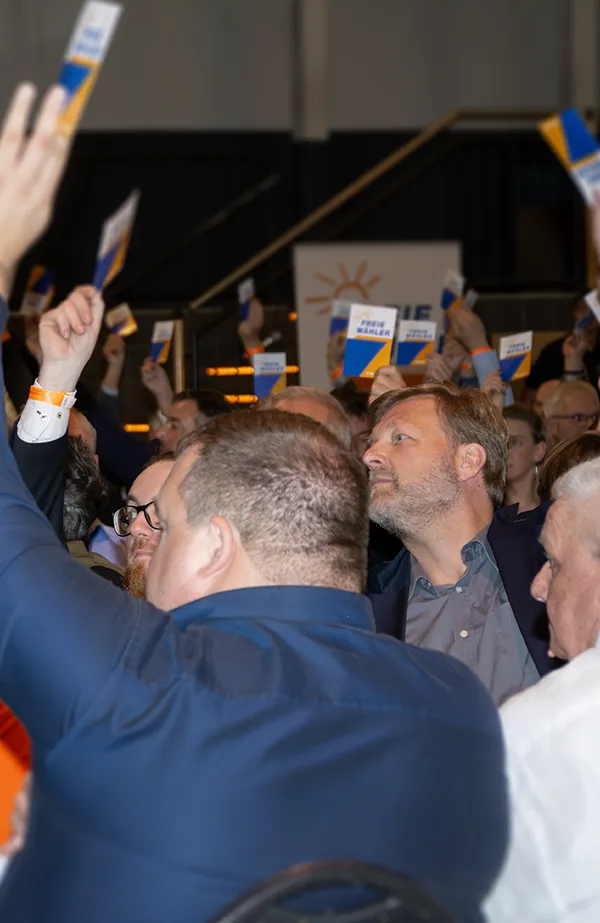 FREIE WÄHLER halten Stimmkarten hoch.